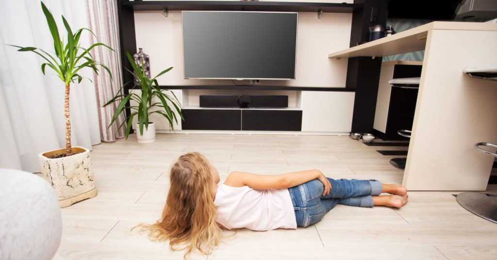 Young girl laying on a heated floor watching tv