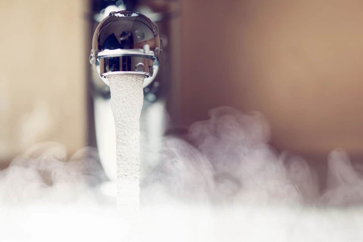 Hot water flowing from a modern faucet with steam rising, illustrating energy-efficient water heating.